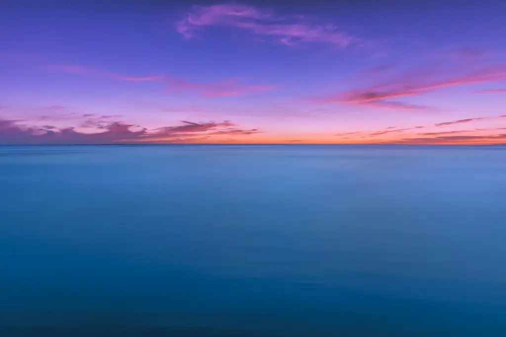Agua en calma y una franja larga de color donde el cielo se encuentra con el mar